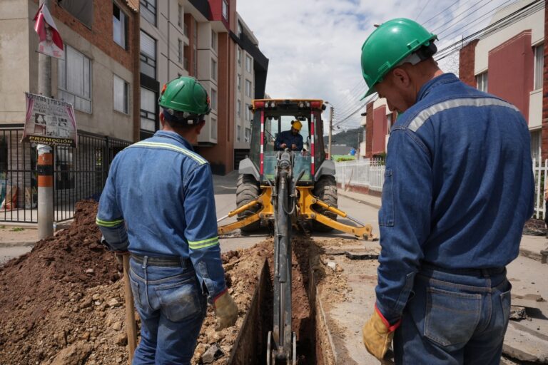 Dos funcionarios de EMPODUITAMA con una retroexcavadora haciendo trabajos en la calle.